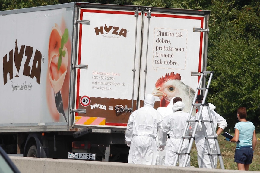 Forensic officers stand by a truck containing a large number of dead migrants