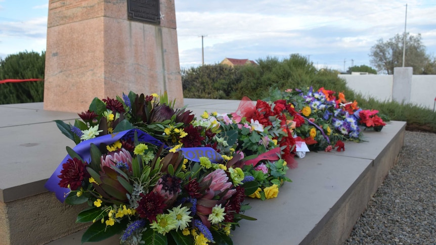 Floral wreathes laid at the base of a war memorial.