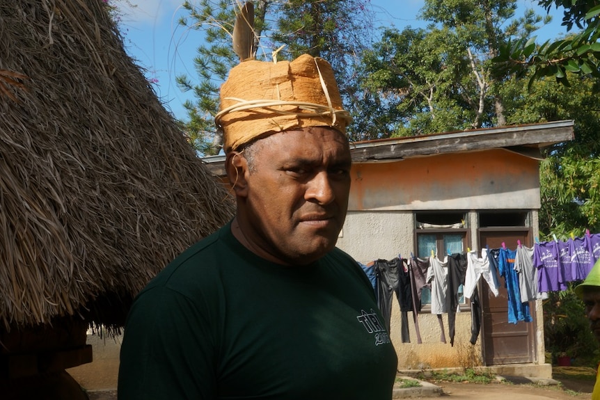 Tribal chief Cyprien Kawa standing in front of a clothline.