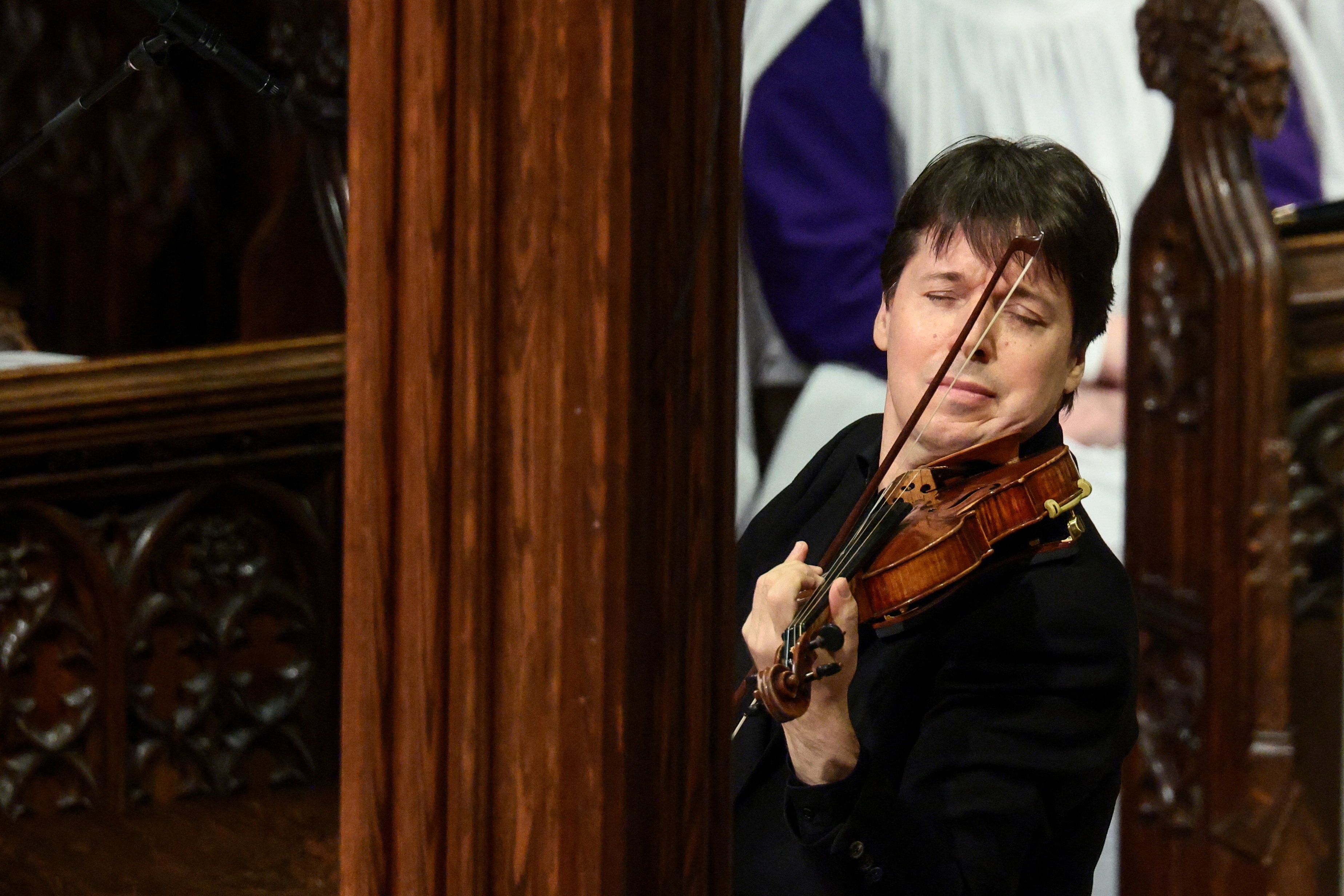 A man plays a violin in a cathedral.