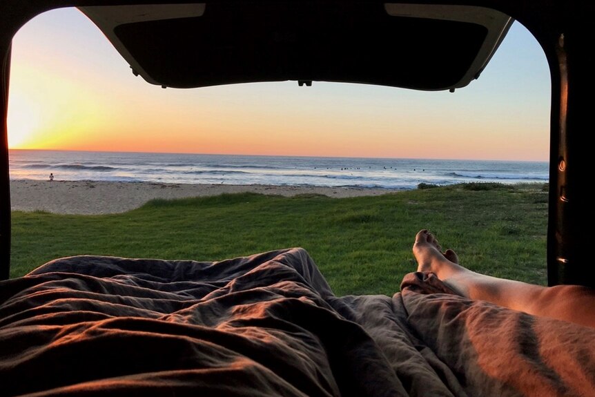 An image of a sunrise over the ocean from the point of view of a van owner
