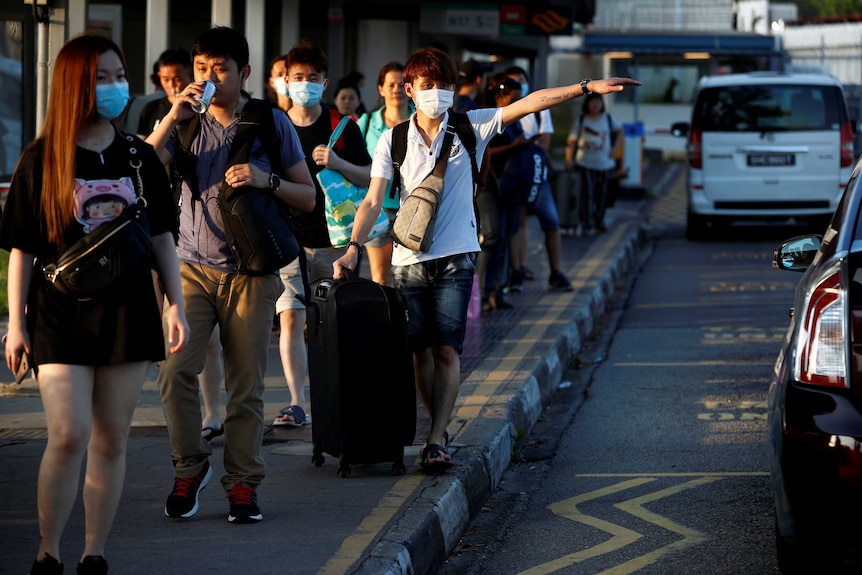 People waring masks line up for cabs in Malaysia.