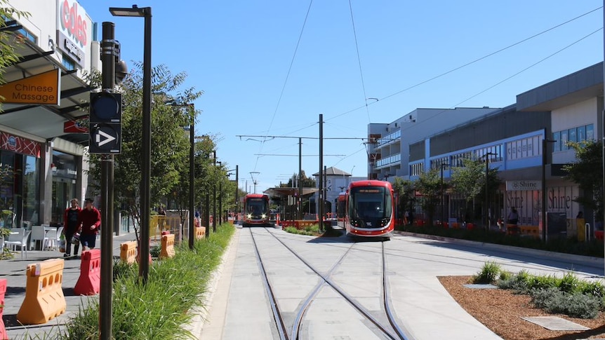 A light rail vehicle sits on the tracks in Gungahlin on a clear sunny day.