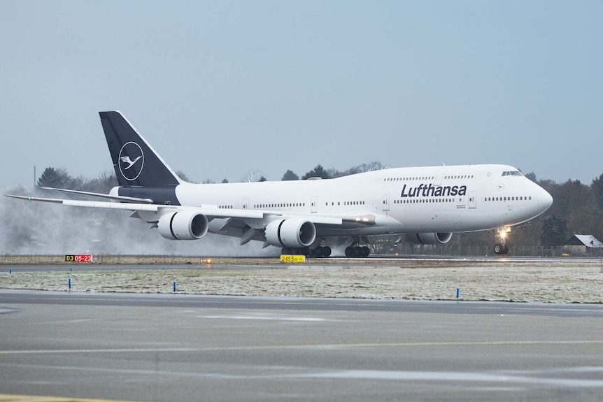 A passenger plane with navy blue branding lands on a runway.