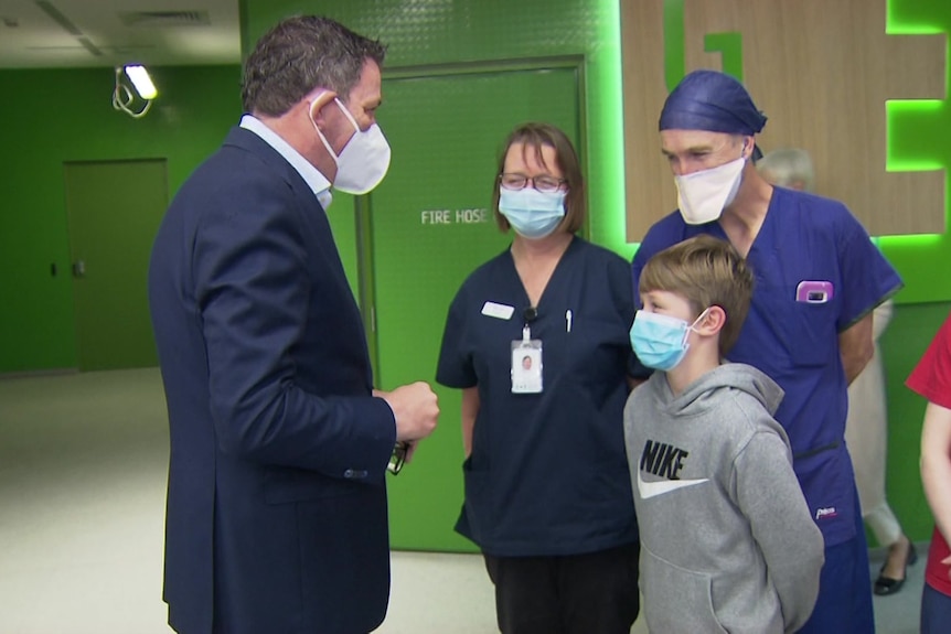 Daniel Andrews talking to medical staff in masks