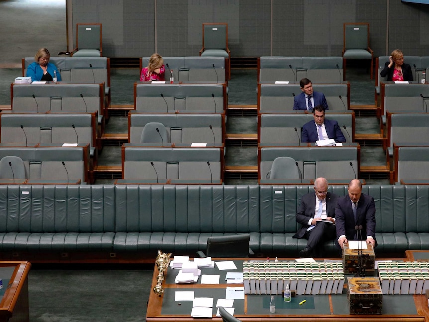 Seven Coalition members, including PM Scott Morrison, sitting in an almost empty parliament.
