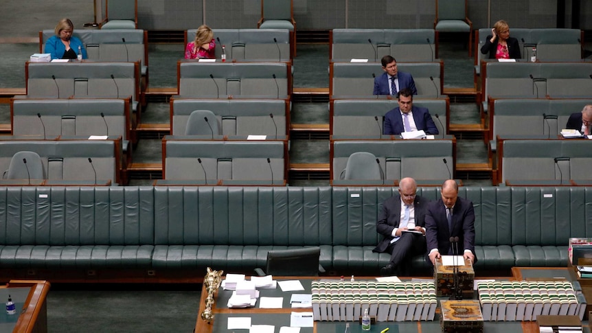 Seven Coalition members, including PM Scott Morrison, sitting in an almost empty parliament.