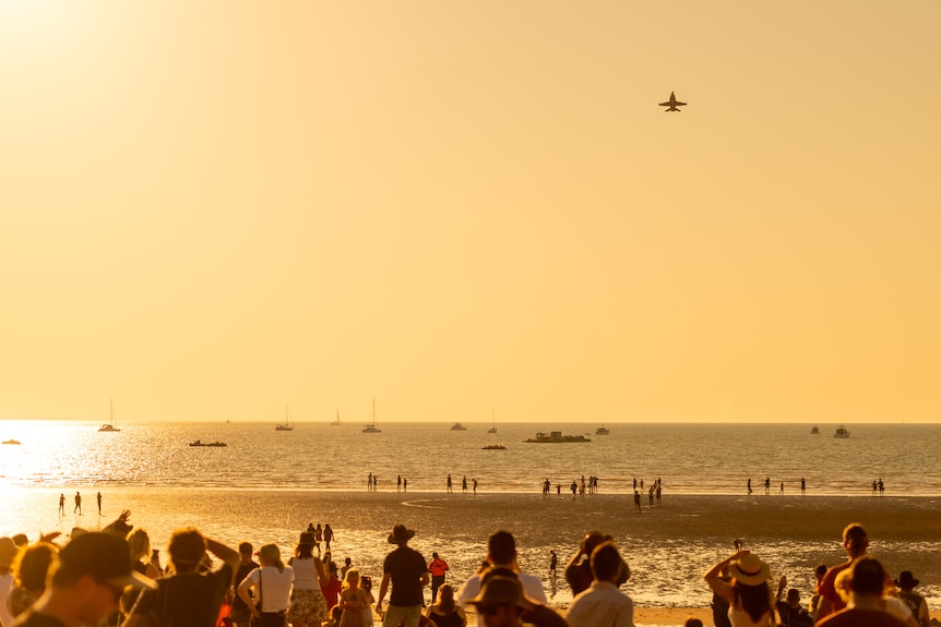 F/A-18 Hornets fly overhead in front of a crowd furing sunset at Mindil Beach in Darwin.