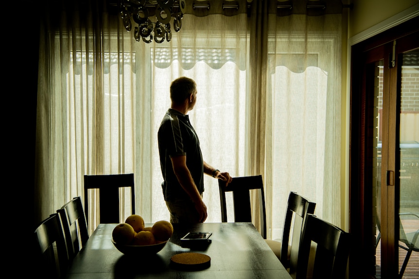 A man, de-identified, looking out a window.