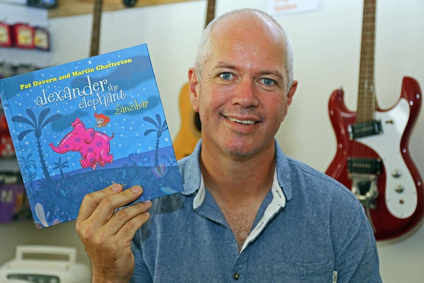 Grinspoon guitarist Pat Davern holds up his new children's book Alexander the Elephant in Zanzibar