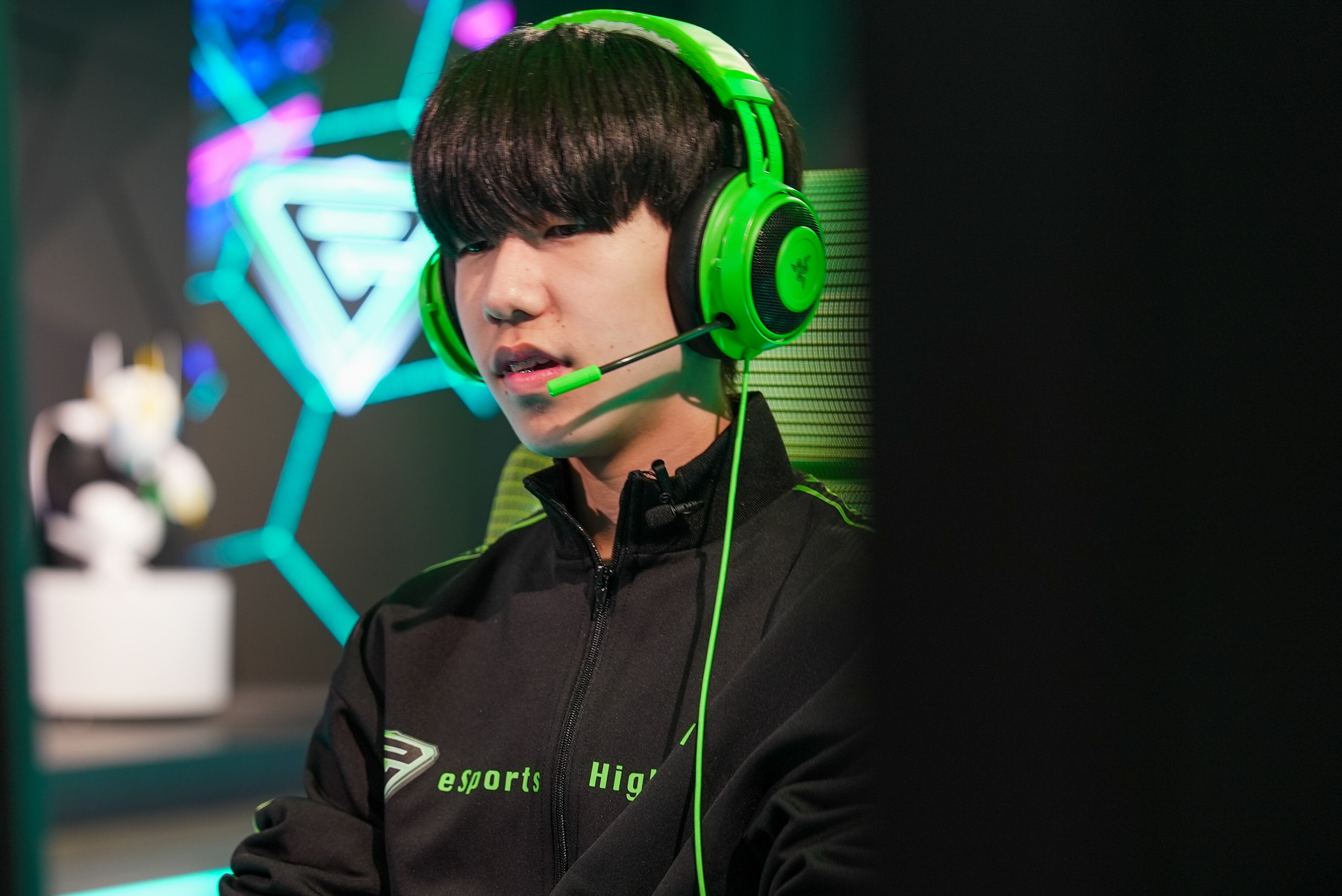 Close de um estudante japonês com fones de ouvido olhando para um computador.