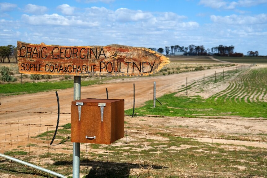 A sign with the names of the farm owner's pointing to a long dusty track