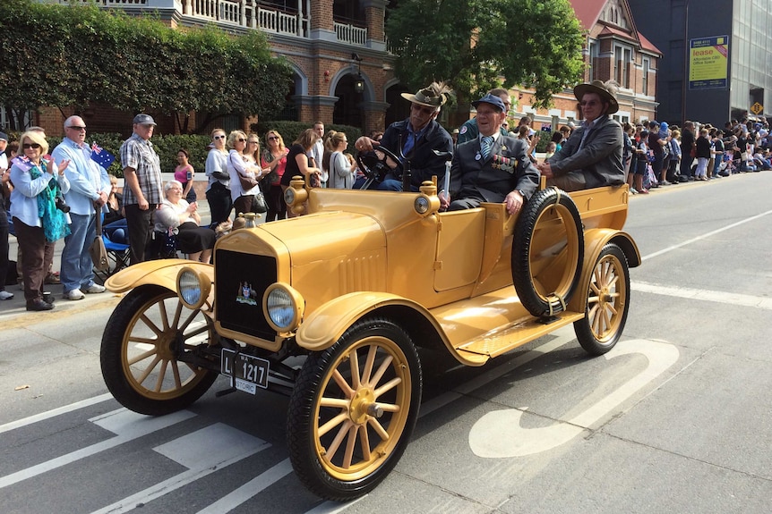 Crowds clap to show their appreciation for veterans in yellow car in Perth