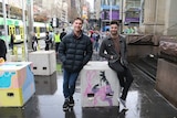 Calum Morgan and Finlay Darrah lean on bollards painted in bright colours in Melbourne's CBD.