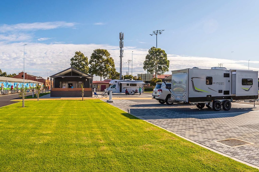 Caravans parked next to grass with a mural of horses in the background.