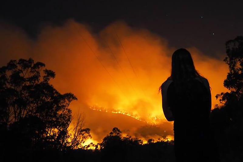 Silhouette of woman watching bushfire at night near Agnes Water.
