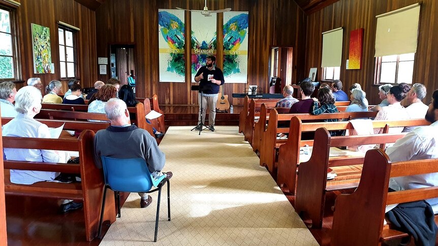 A small timber church with parishioners seated in the pews.