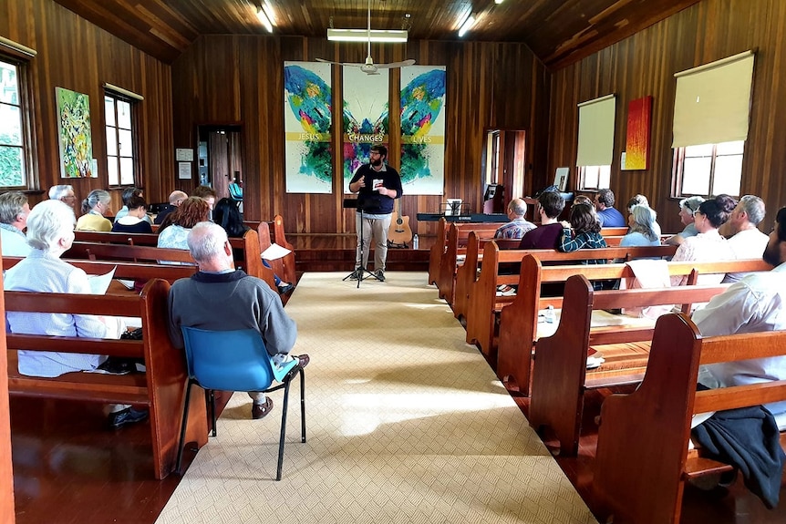 A small timber church with parishioners seated in the pews.