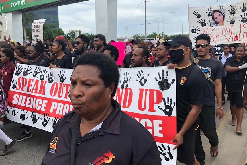 A group of protesters walk down a Port Moresby road holding signs