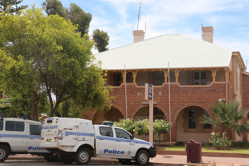 A two-storey brick building with police utes out the front