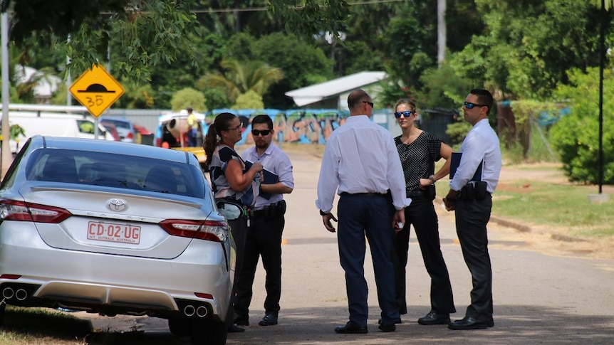 Detectives gather by a car