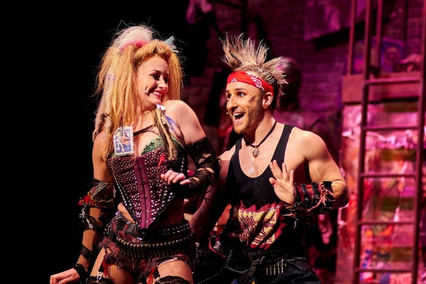 Man and woman dressed up in costume while performing on stage.