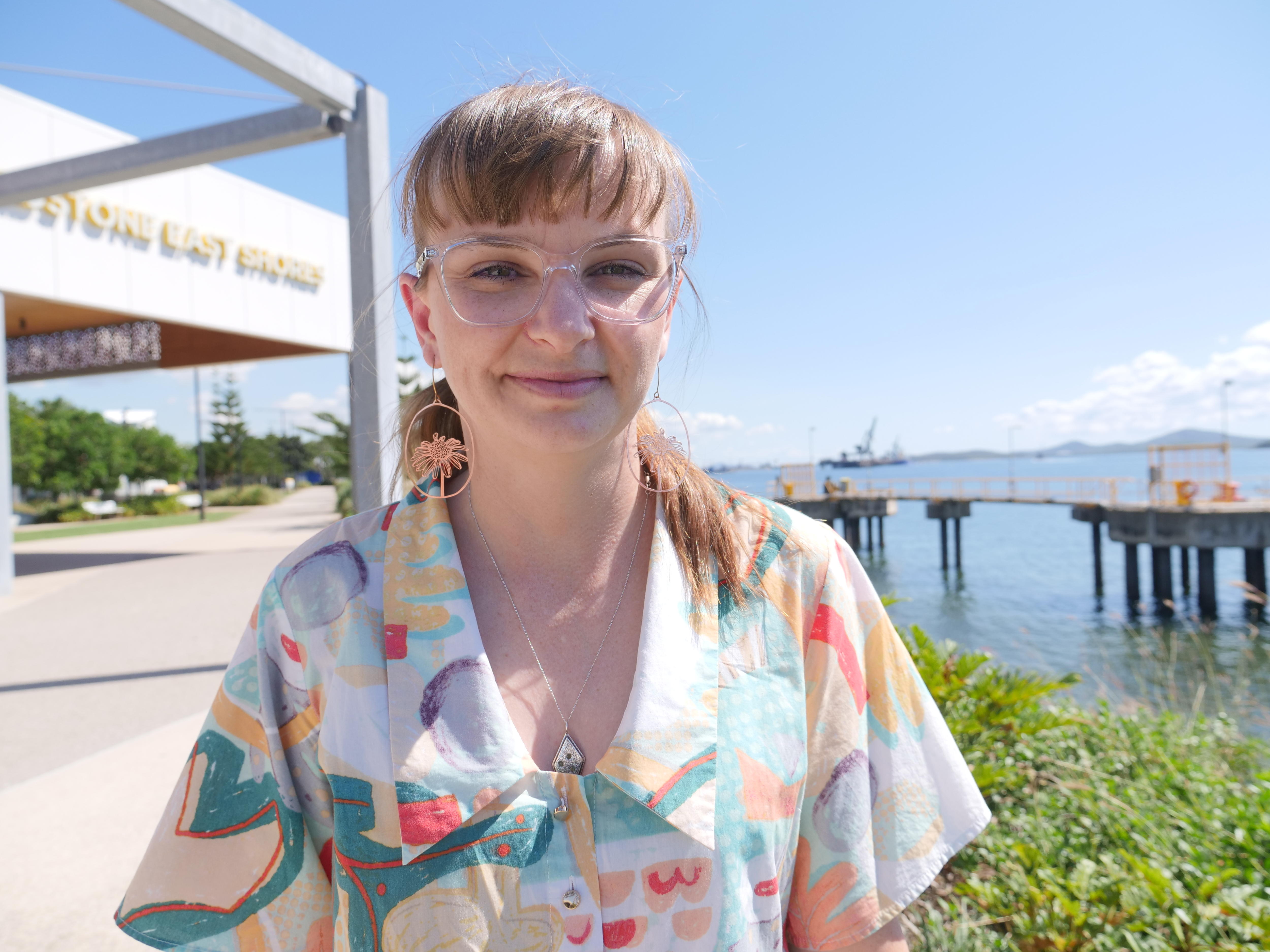 A woman with brown hair, a fringe and glasses smiling