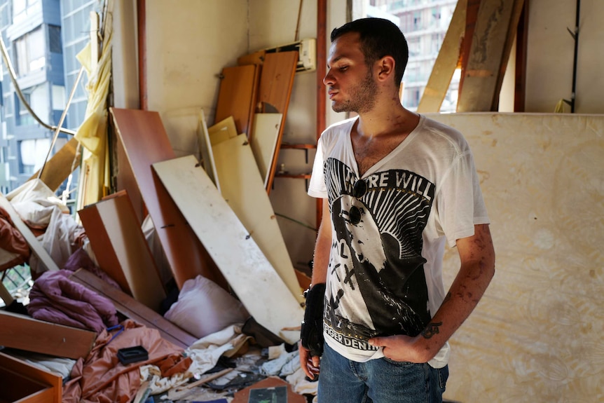 A young man stands in a destroyed apartment