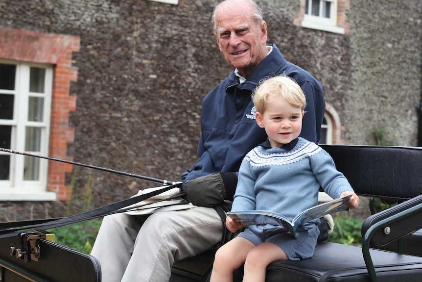 .Prince George with his great-grandfather, Prince Philip, on a carriage on the Sandringham Estate