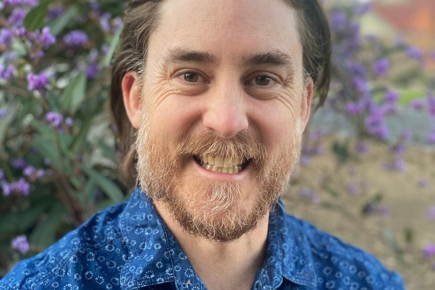 Man in blue shirt smiles at camera.