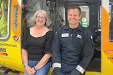 A woman and a rescue crewman standing next to a helicopter.