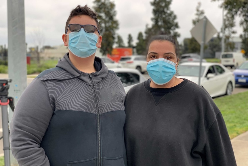 Luci Larubina and her son Patrick Larubina wearing blue surgical masks and looking at the camera.