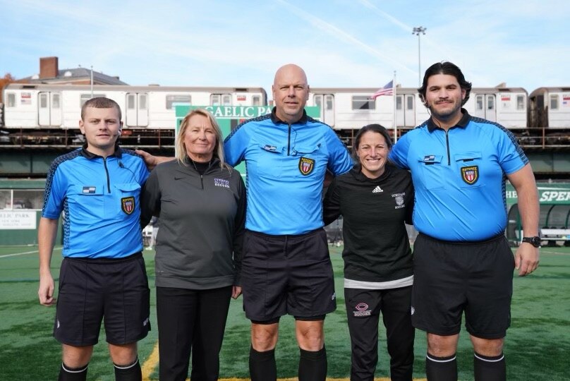 Two women coaches stand next to referees before a match