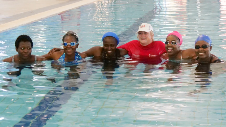Six women in the swimming pool smiling. 