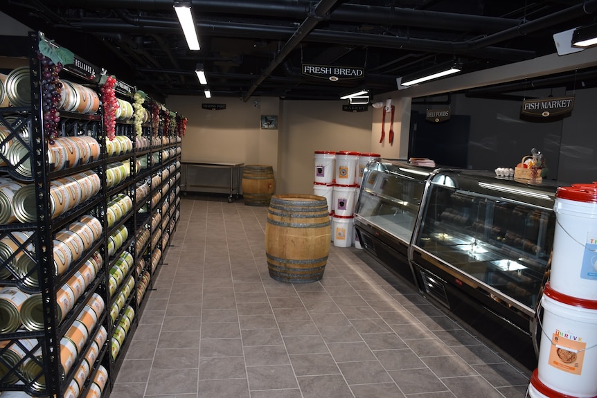 An empty store with some food on the shelves in an underground bunker.