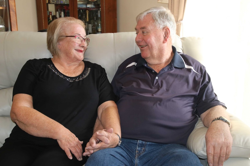 Ruth and John sitting on lounge facing each other.