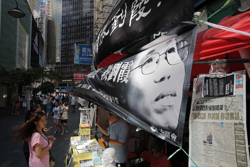 People are standing by a stall decorated with a black and white banner of Liu Xia.