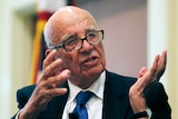 Rupert Murdoch gestures with both hands while speaking.