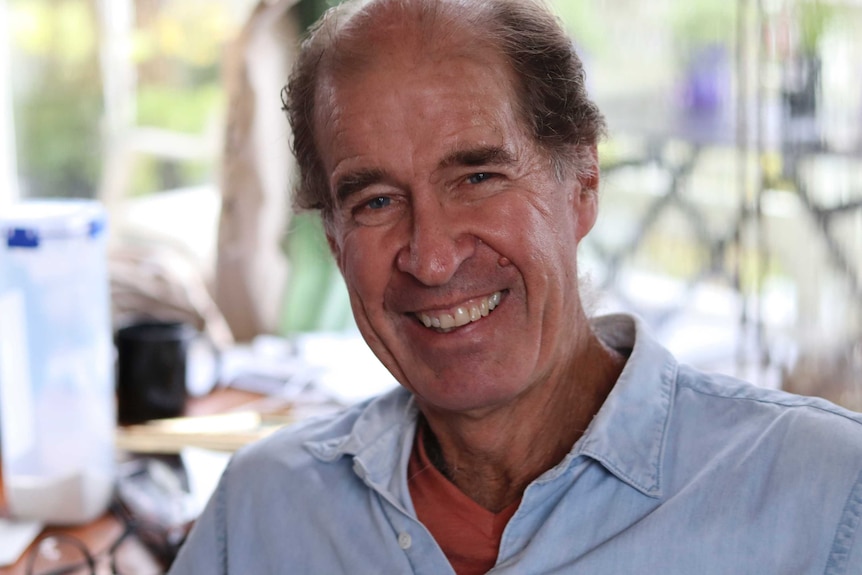 A 70-year-old man smiles in a portrait photo