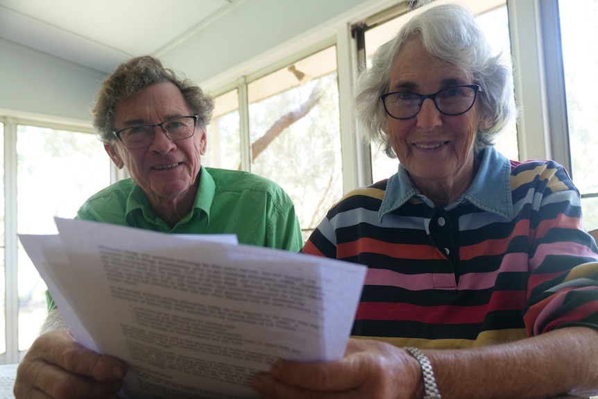 Man and woman looking up from a pile of papers at their kitchen table. 