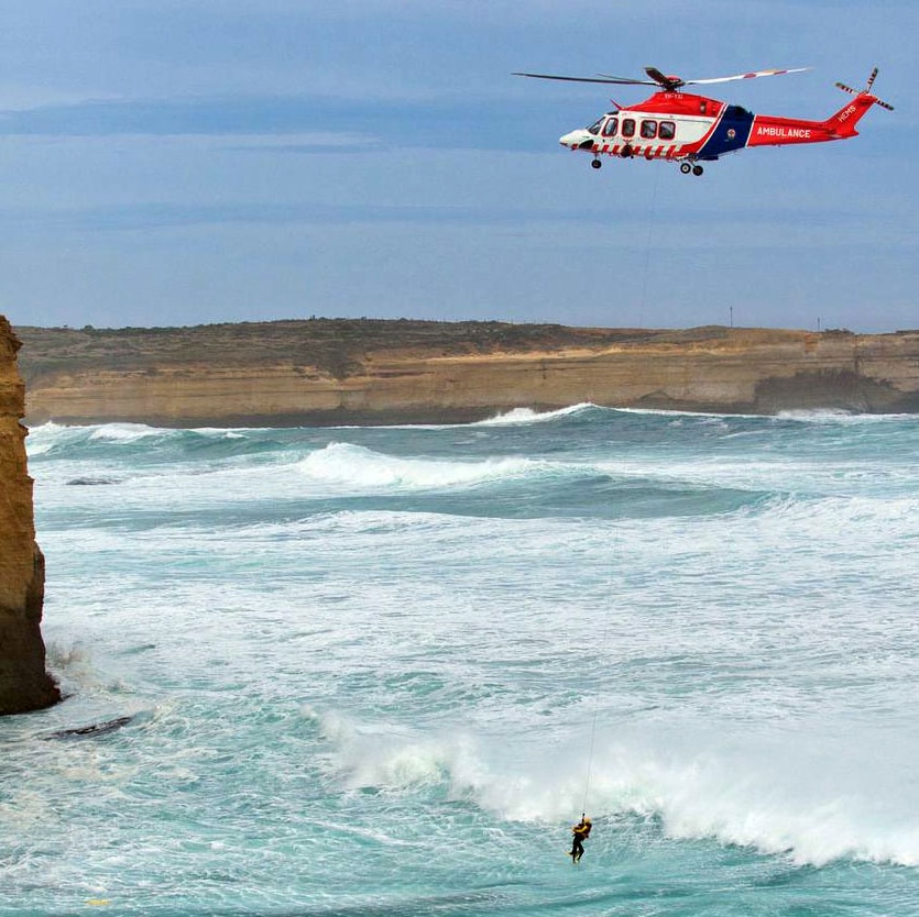 An ambulance helicopter winches a man to safey off the coast of Port Campbell.