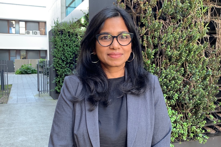 Dr Nusrat Homaira is wearing a blazer and glasses and standing outside