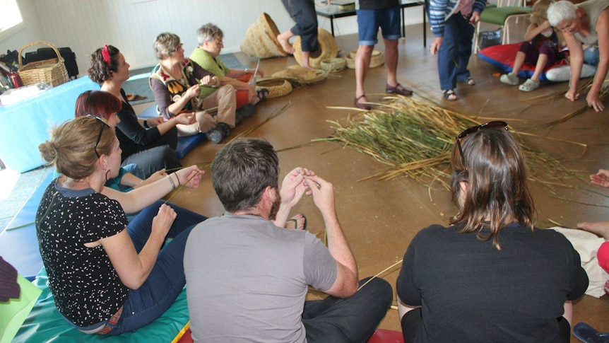 Basket weaving workshop participants sit in a circle, preparing to weave a basket from grass gather in Gippsland, Victoria.