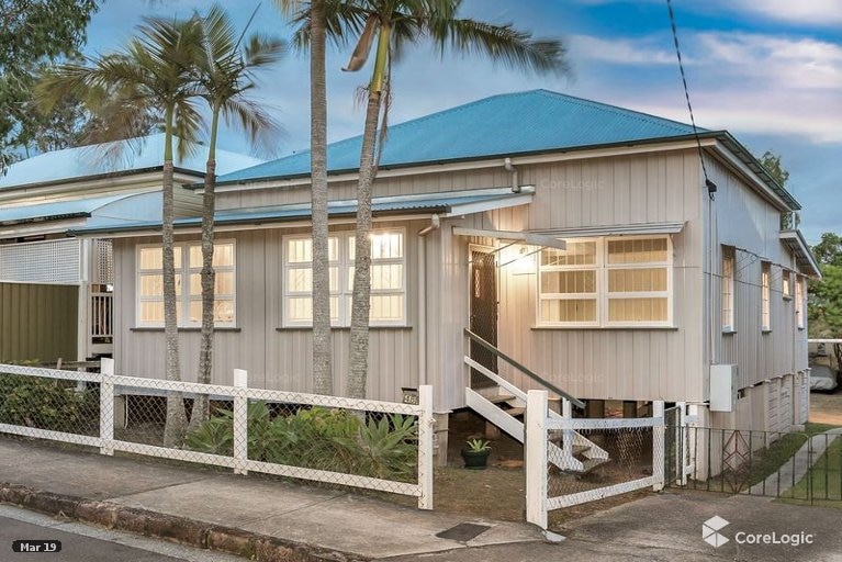 A one-storey beige house with a tin roof on cement stilts.