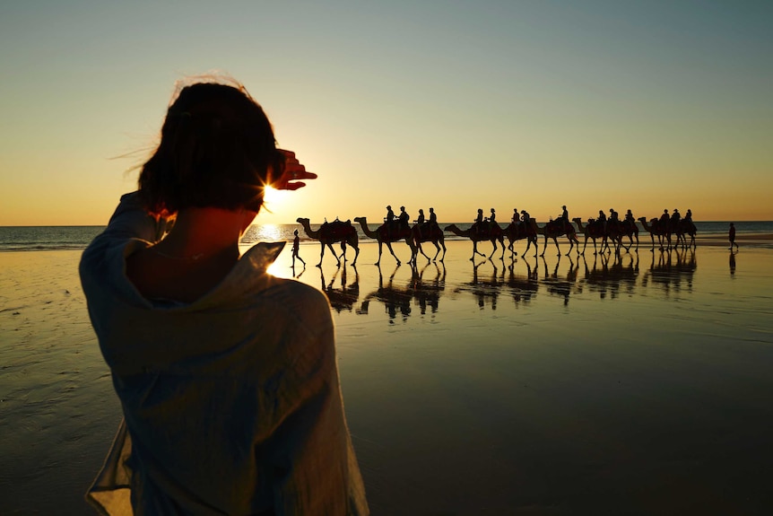 A woman watches a camel train at Broome's Cable Beach.