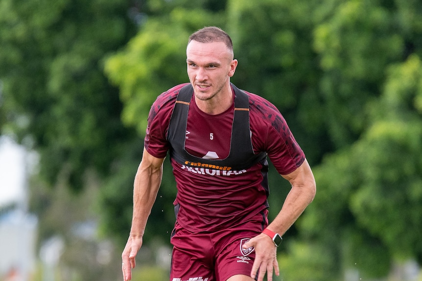 Tom Aldred, who has short hair and is wearing a maroon jersey, runs at a training session.