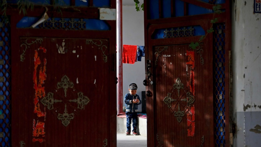 A Uyghur child plays alone in the courtyard of a home in Xinjiang.