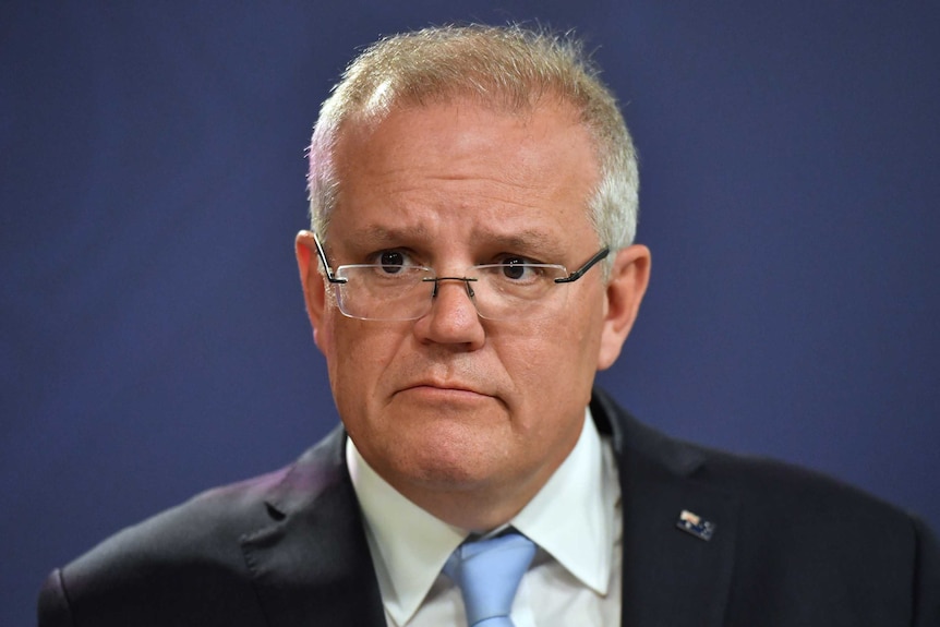 A close up photo of Scott Morrison with a serious expression on his face. He is wearing a suit.