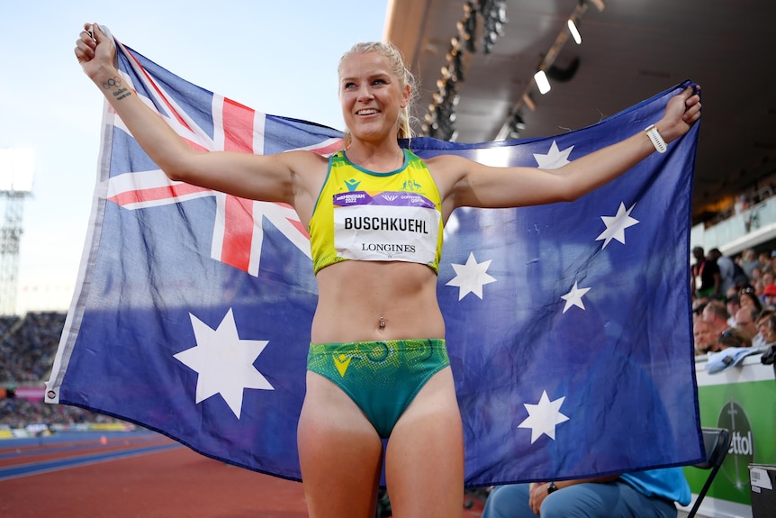 Australian long jumper Brooke Buschkuehl holds a national flag after winning silver at Birmingham 2022.