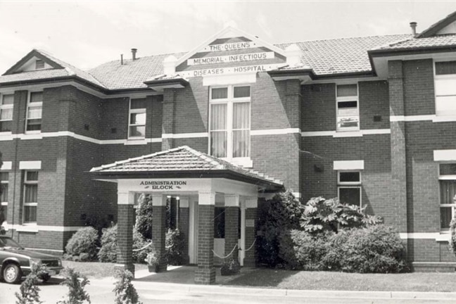 A black-and-white photograph shows a brick building with signage for Queen's Memorial Infectious Diseases Hospital.